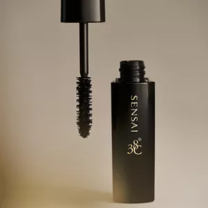 Close up of Lash Volumiser opened on neutral surface showcasing the brush and texture